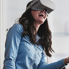 Brunette in denim blouse wearing grey oculus go and smiling