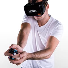 Man wearing white t-shirt using the OSVR headset and remote controls in his hands